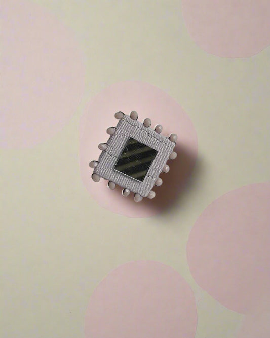 Pastel purple square finger ring with beads and mirror on white backdrop