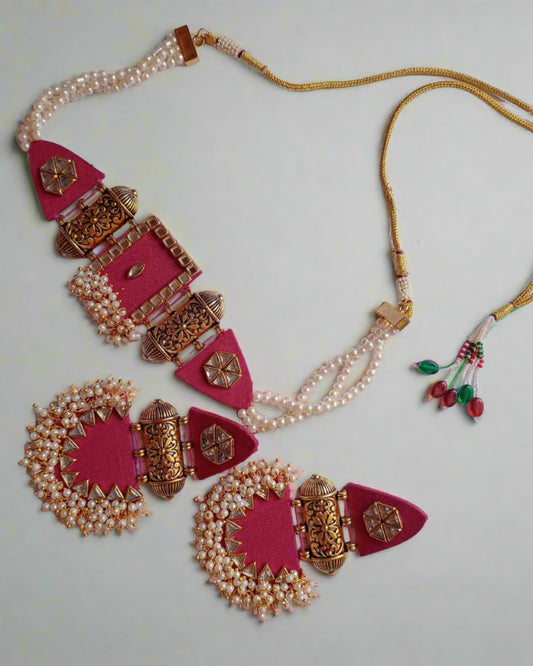 Pink and golden choker necklace and earrings with white beads on white grey backdrop