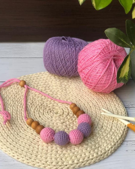 Pink and purple crochet necklace with brown beads on beige crochet backdrop