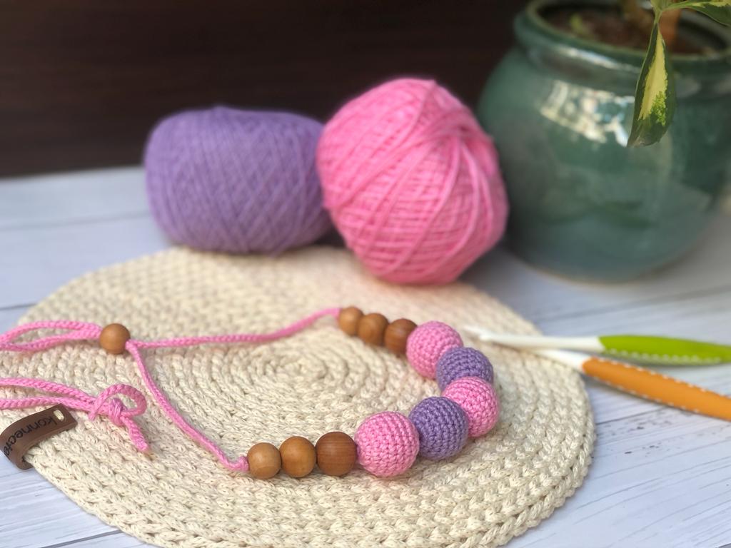 Pink and purple crochet necklace with brown beads on beige crochet backdrop