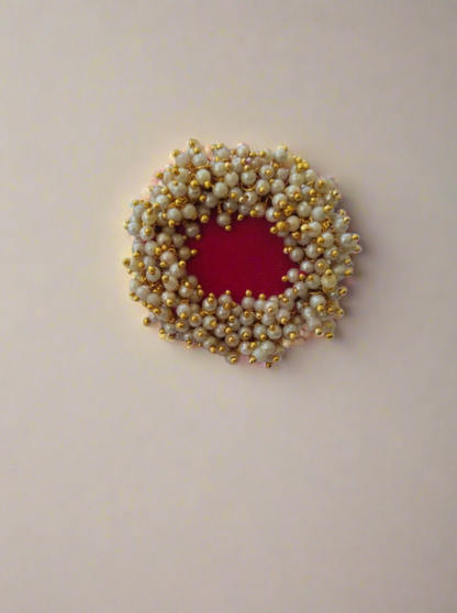 Red finger ring with white golden beads on white backdrop