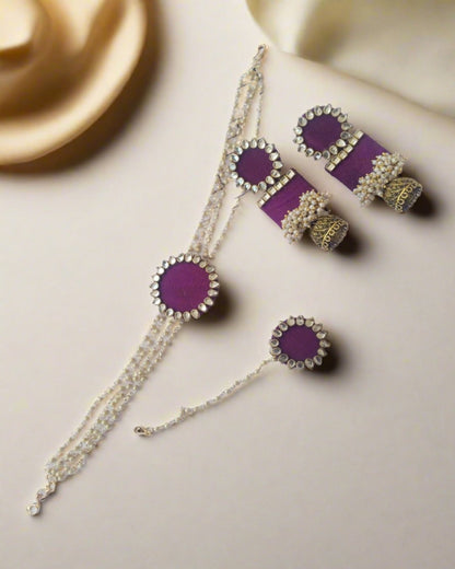 Purple choker necklace with kundan details and matching earrings and tika on white backdrop 