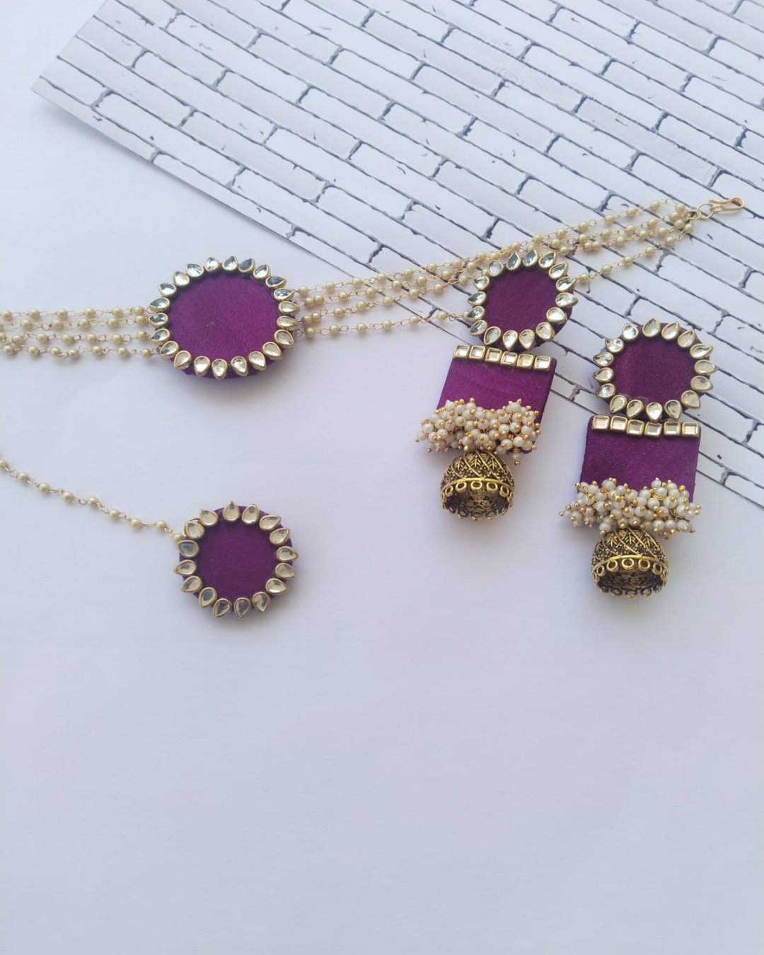 Purple choker necklace with kundan details and matching earrings and tika on white backdrop 