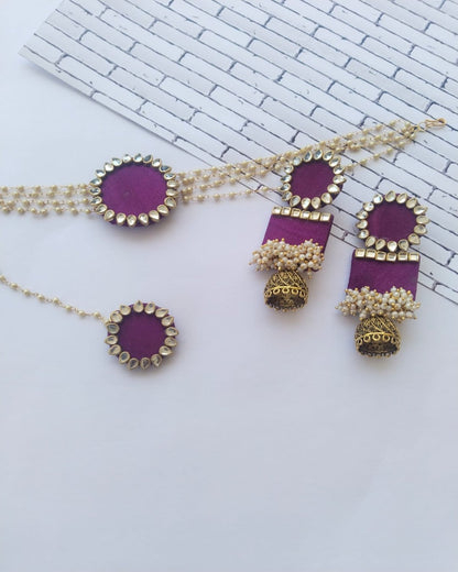 Purple choker necklace with kundan details and matching earrings and tika on white backdrop 