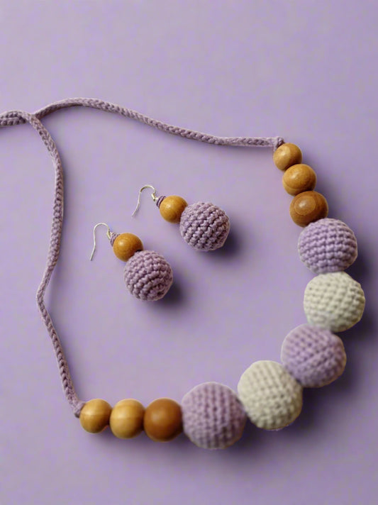 Purple and white crochet necklace with brown beads on grey white backdrop