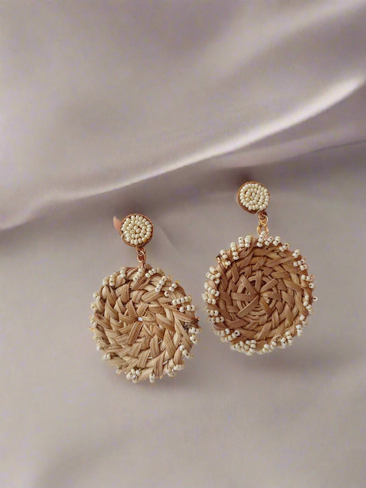 Palm holding bamboo made round earrings with white beads on white backdrop