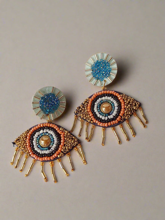 Blue, black and white evil eye beaded earrings on white grey backdrop