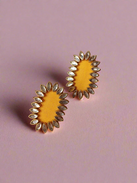 Oval yellow studs earrings with kundan border on white backdrop