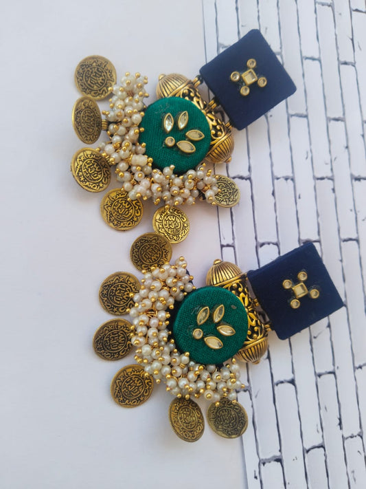 Blue and dark green earrings with golden tabiz, coins and white beads on white backdrop