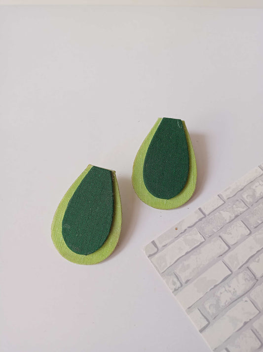 Light and dark green avocado shaped studs earrings on a white backdrop