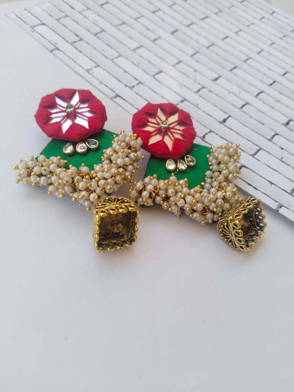 Red and green earrings with mirror work, white beads and golden bottom on white backdrop