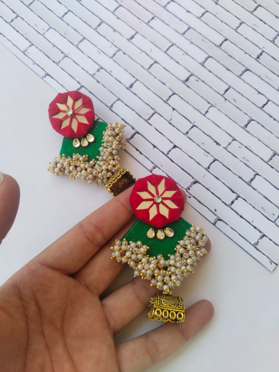 Red and green earrings with mirror work, white beads and golden bottom on white backdrop