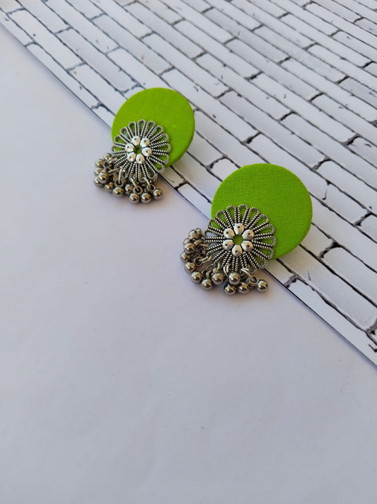 Lime green round earrings with silver charm and ghungroos on white backdrop