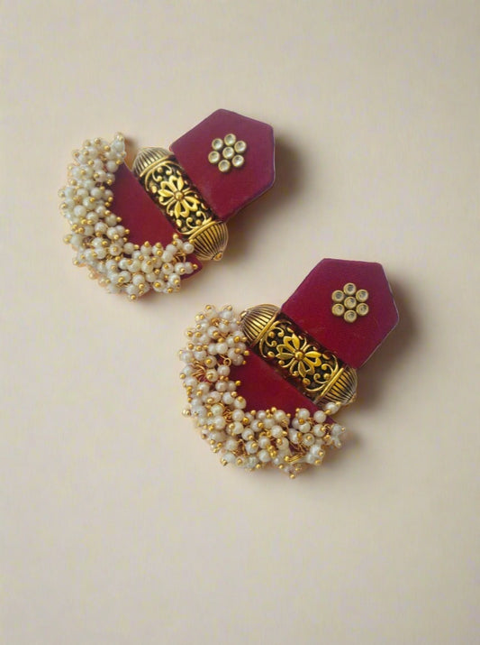 Maroon jhumka earrings with white beads and golden tabiz on white backdrop