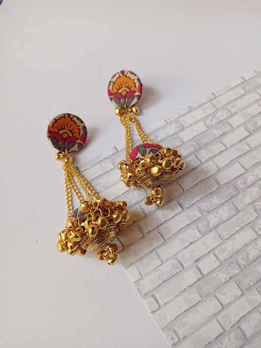 Red printed jhumka with golden chains and ghungroo on white grey backdrop