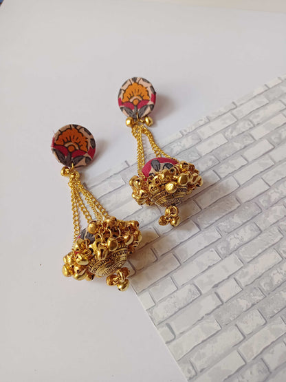 Red printed jhumka with golden chains and ghungroo on white grey backdrop
