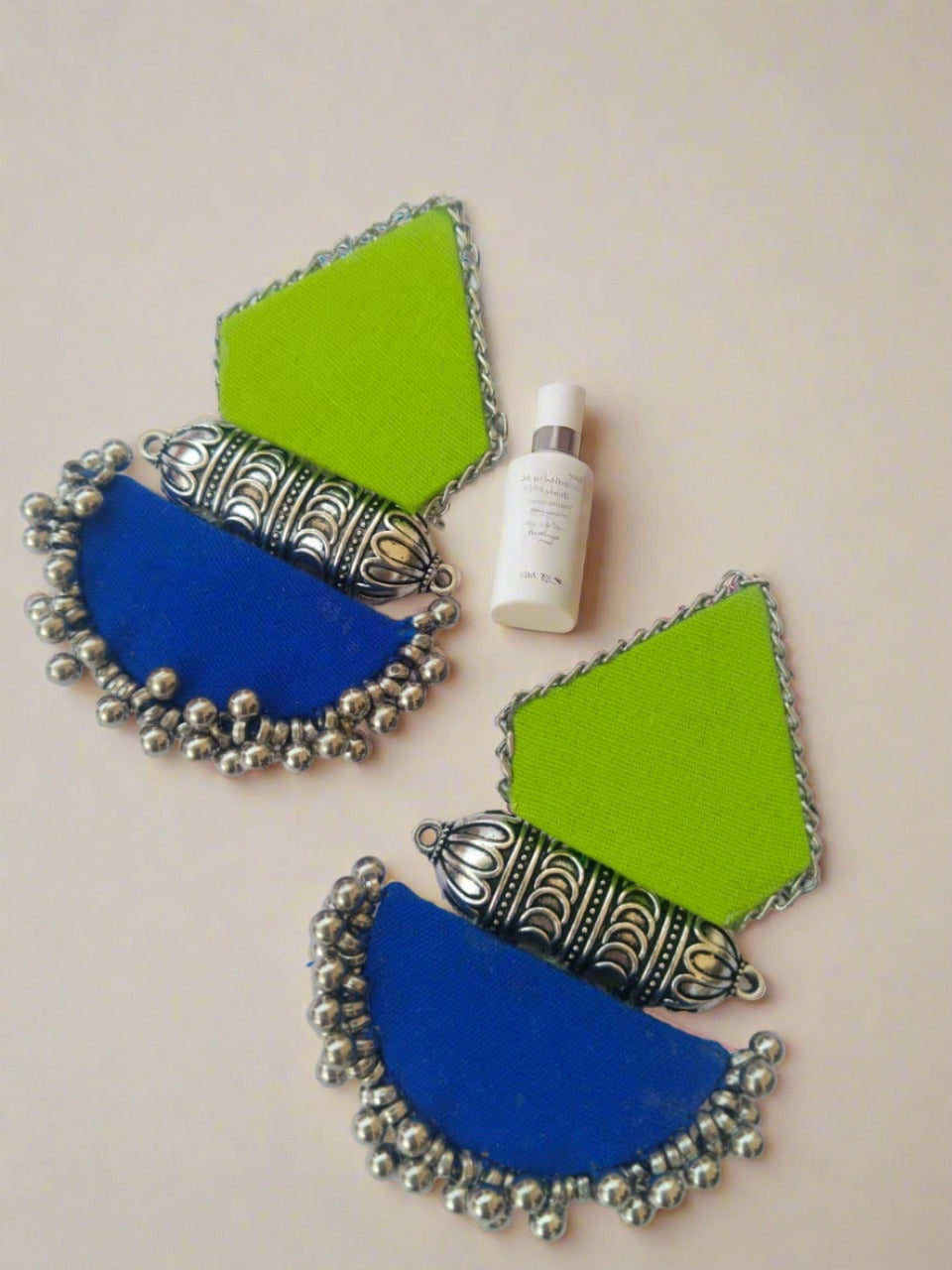 Light green and dark blue earrings with silver tabiz and beads on white backdrop