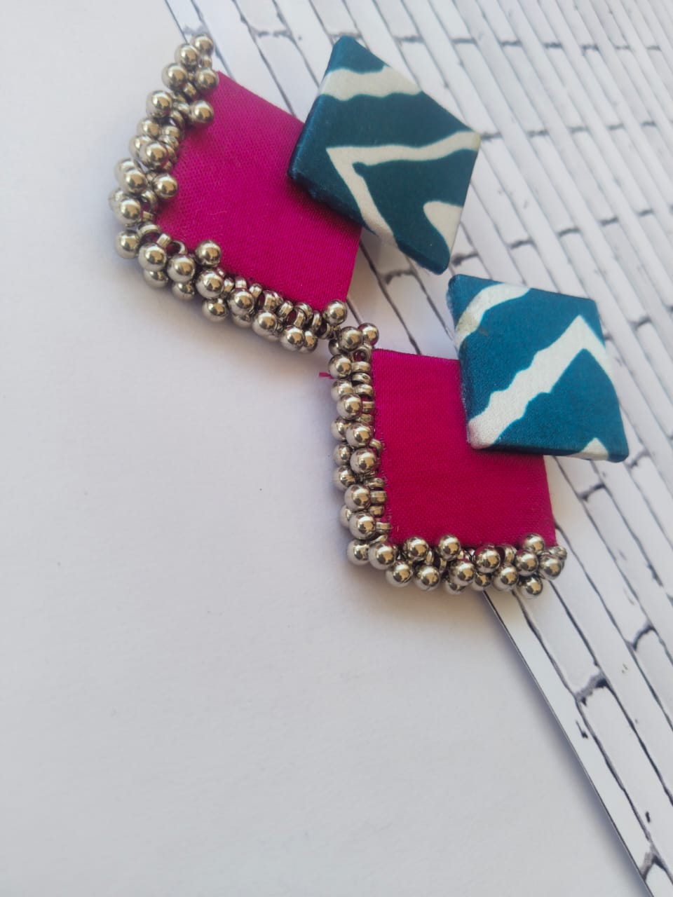 Printed blue and magenta pink earrings with silver beads on white backdrop