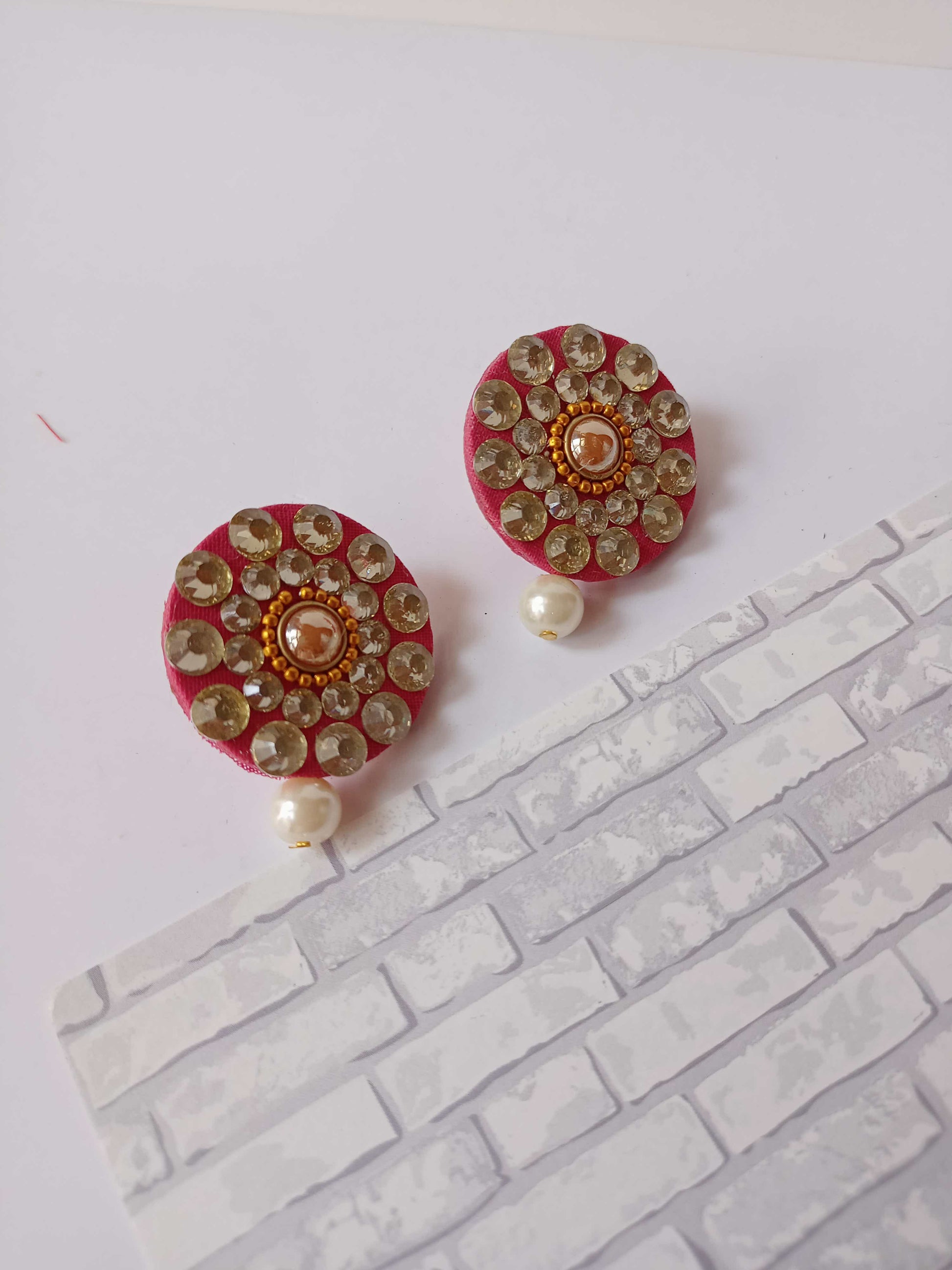 Round pink studs earrings with kundan and white pearl on white backdrop