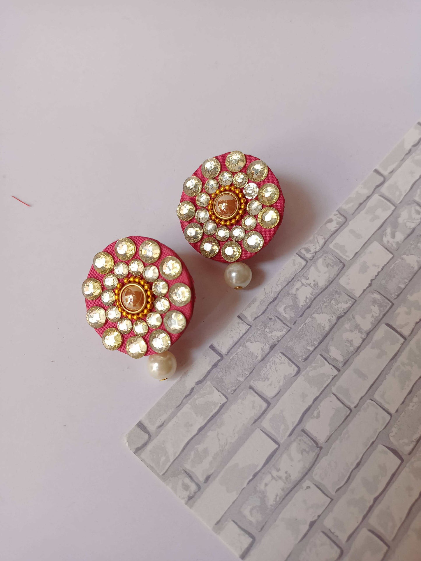 Round pink studs earrings with kundan and white pearl on white backdrop