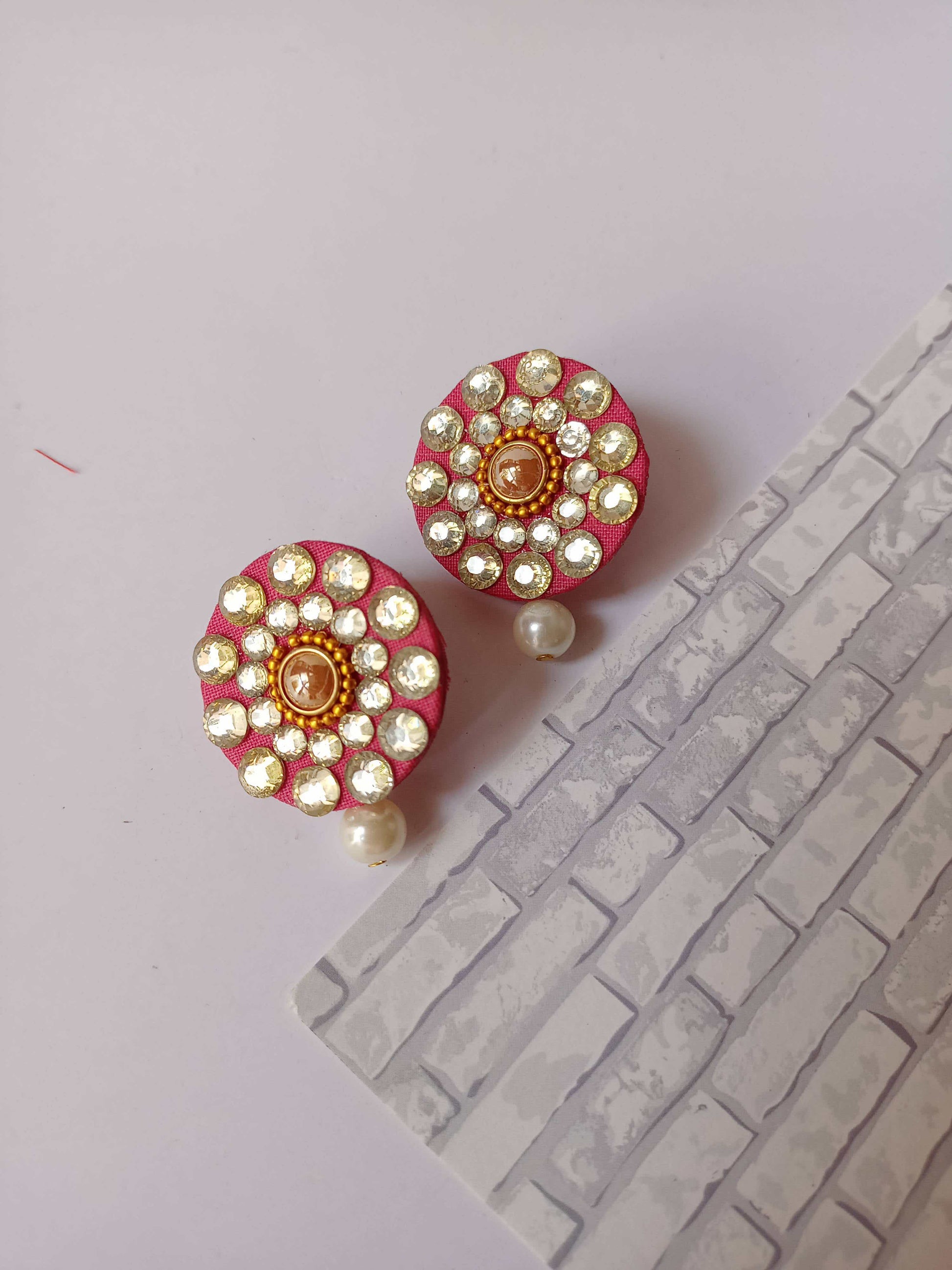 Round pink studs earrings with kundan and white pearl on white backdrop