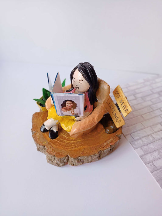 Miniature of a girl reading mini book on a couch kept on white backdrop