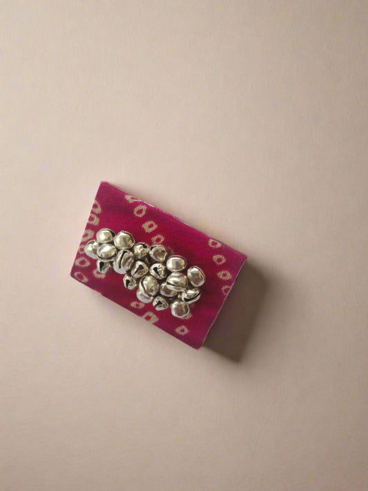 Rectangular shape red bandhani print finger ring with silver ghungroo on white backdrop