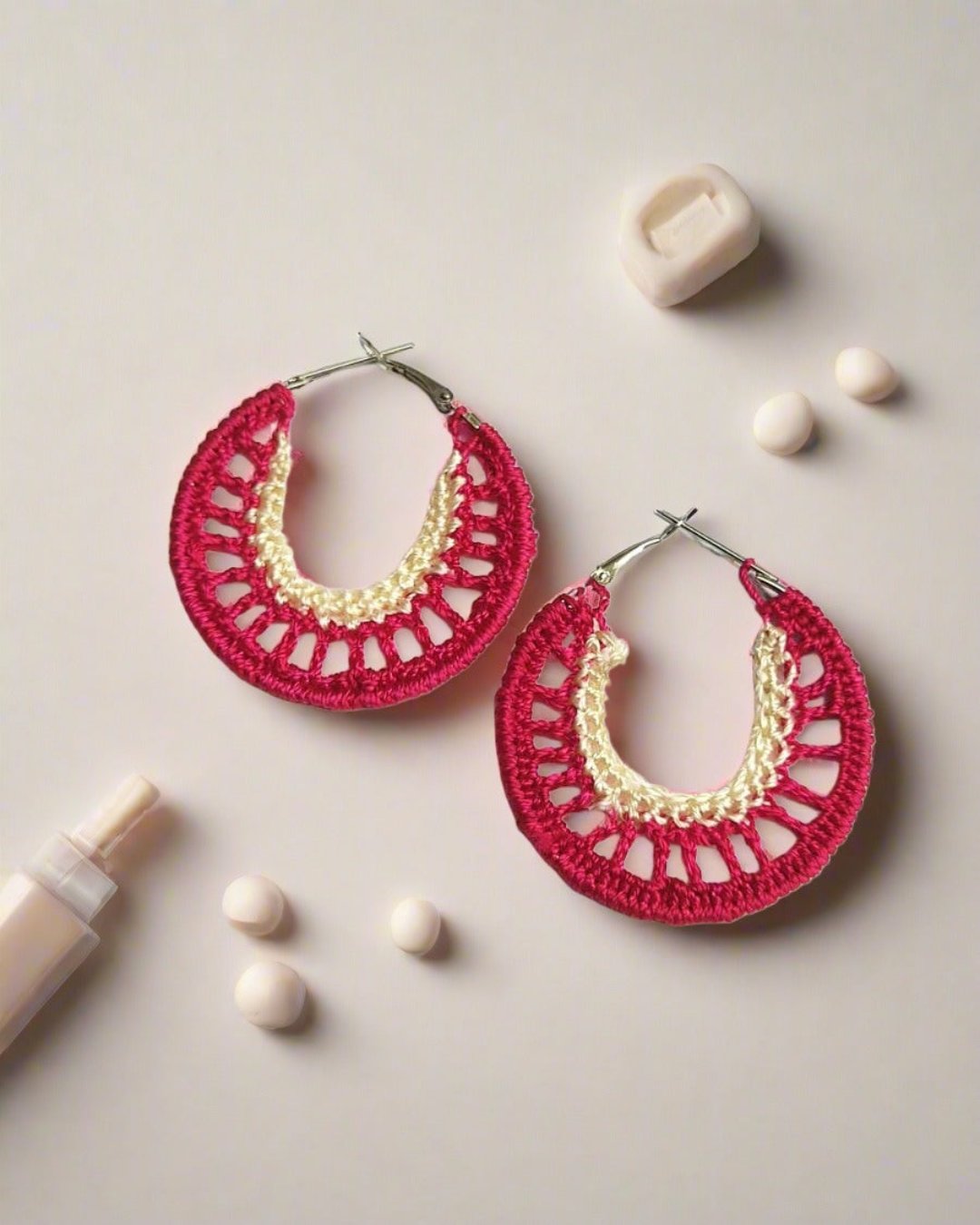 Red and yellow crochet hoops earrings on white grey backdrop