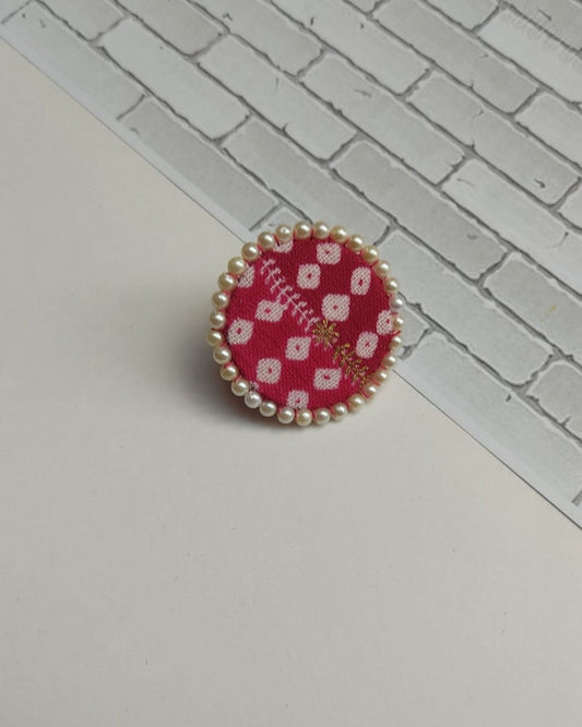 Red bandhani print round finger ring with pearls border on white backdrop
