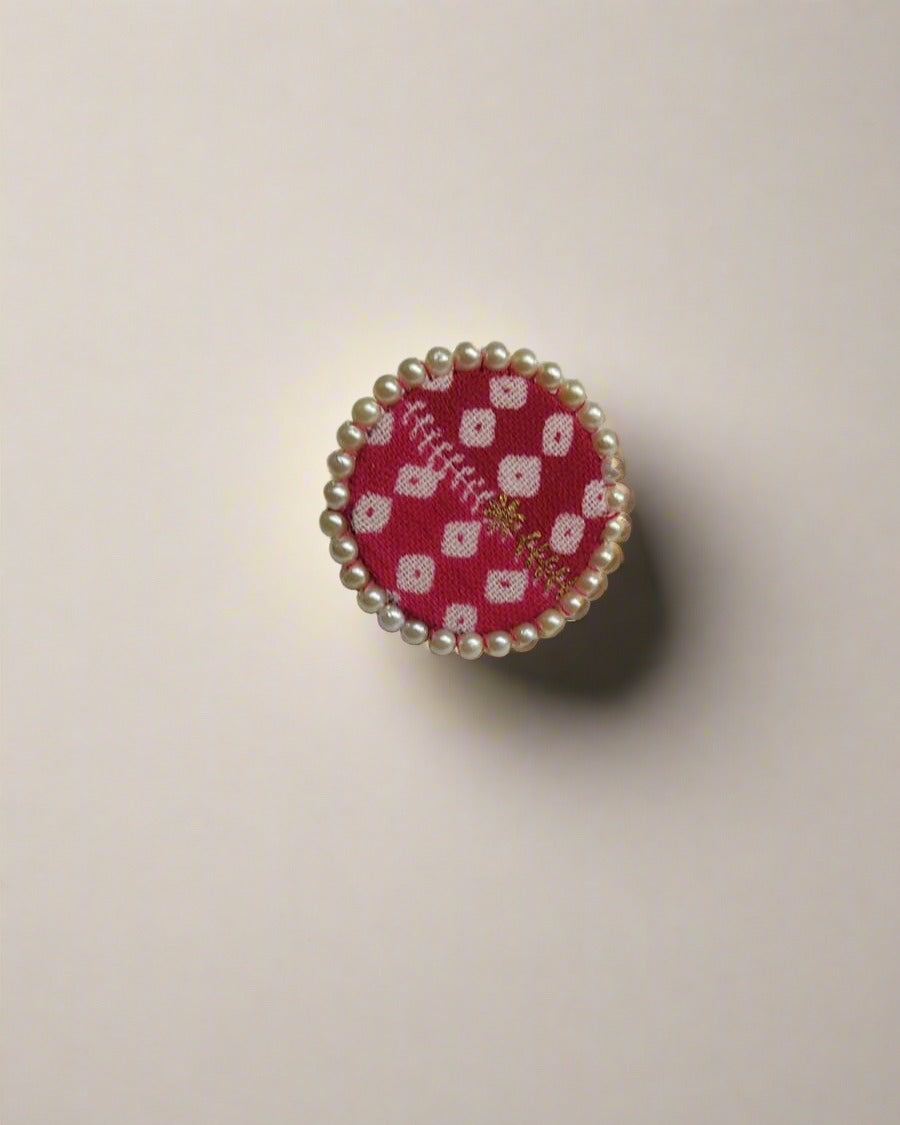 Red bandhani print round finger ring with pearls border on white backdrop