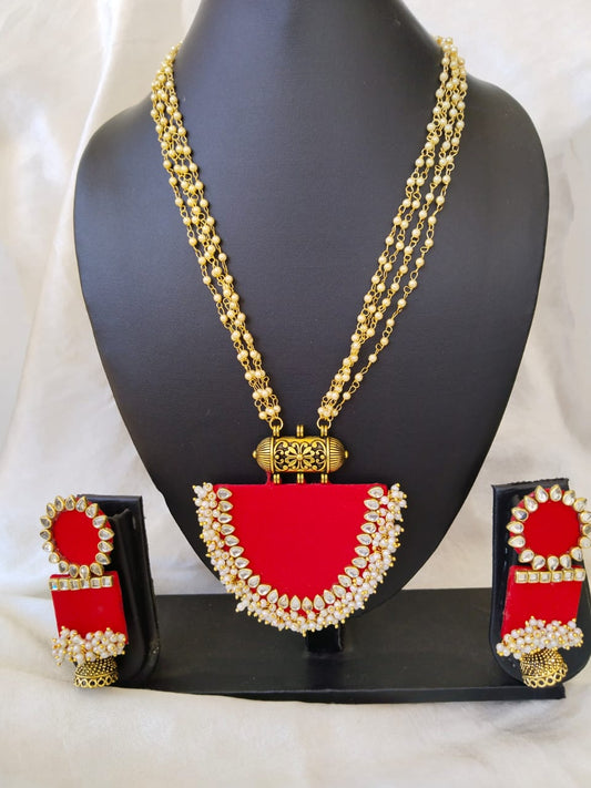 Black necklace and earrings stand with red necklace and earrings with golden beads details