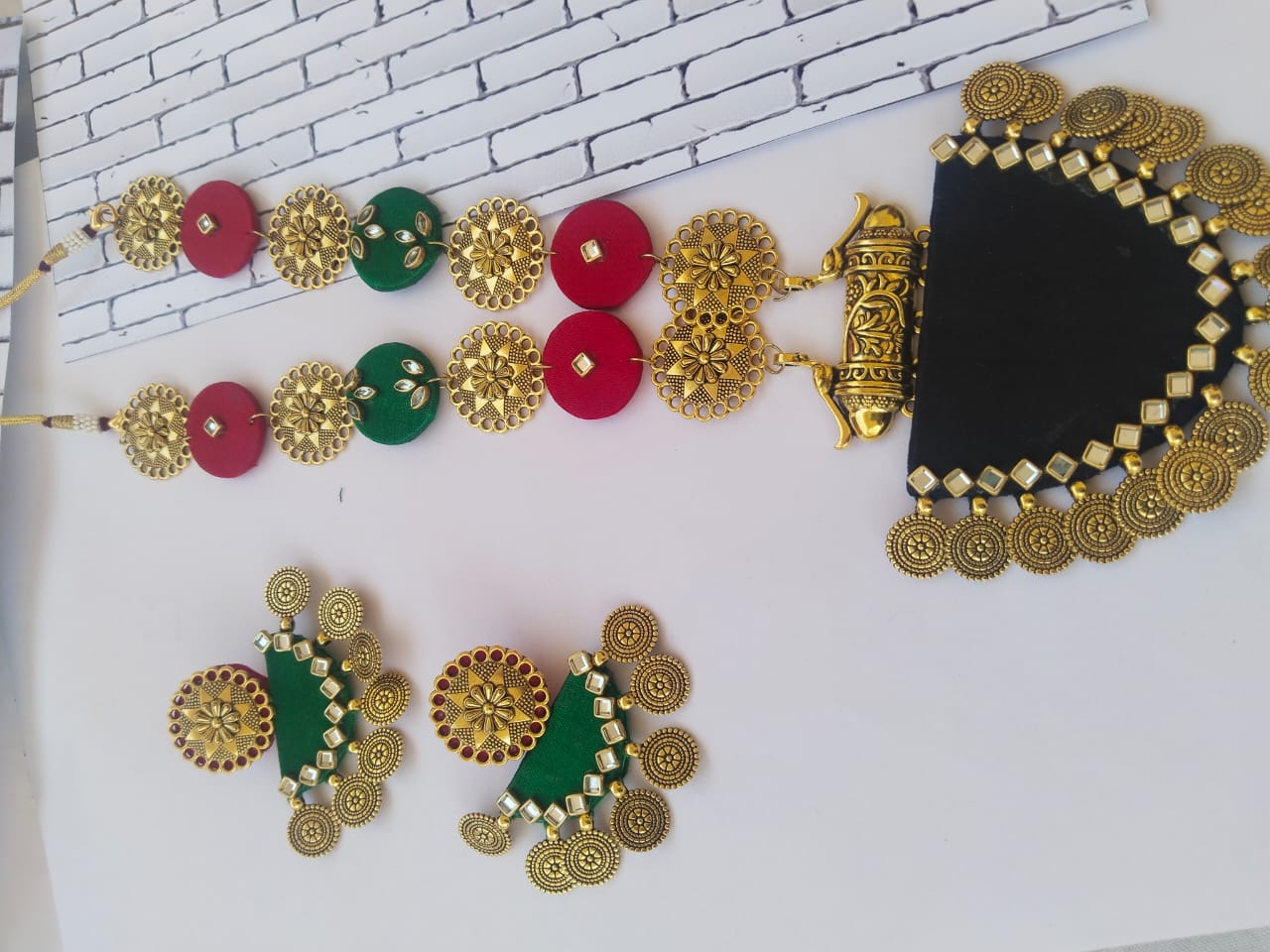 Green black and red necklace with golden coins and kundan on white backdrop