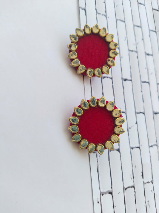 Red mini round studs earrings with kundan border on white grey backdrop