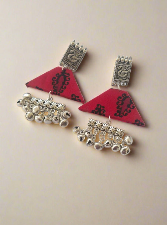 Red printed triangular shape earrings with silver charm and ghungroo on white backdrop