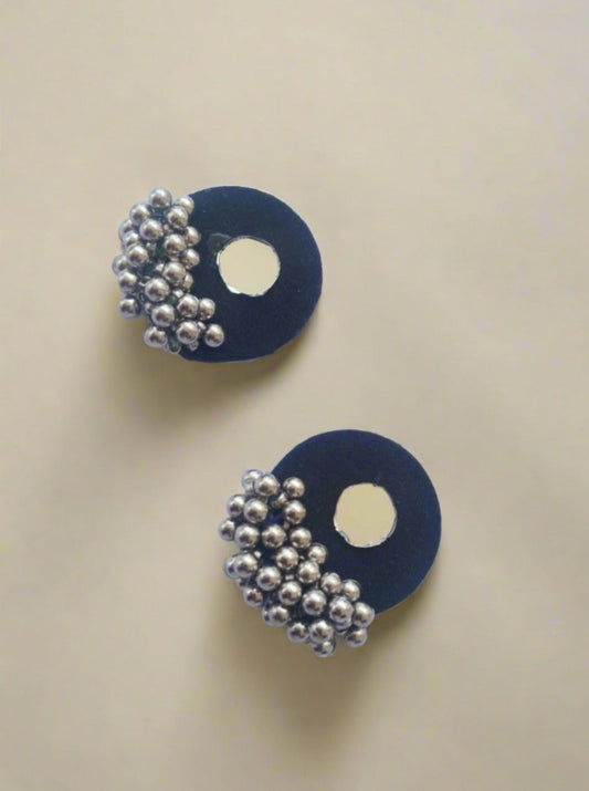 Round blue studs earrings with mirror and silver beads at bottom on white grey backdrop