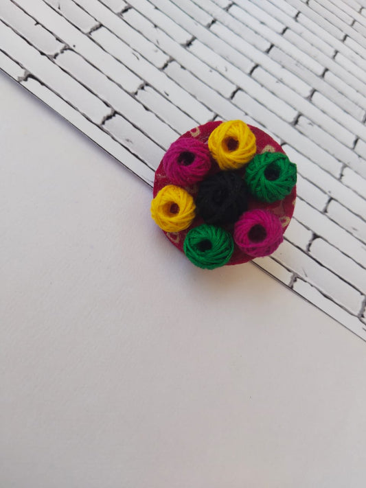 Round fabric finger ring with multicolor details with embroidered threads on white grey backdrop