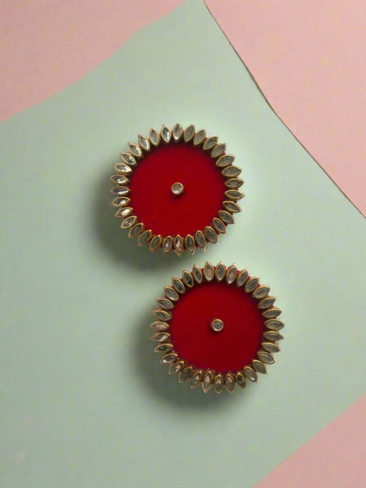 Round red studs earrings with kundan border on white grey backdrop