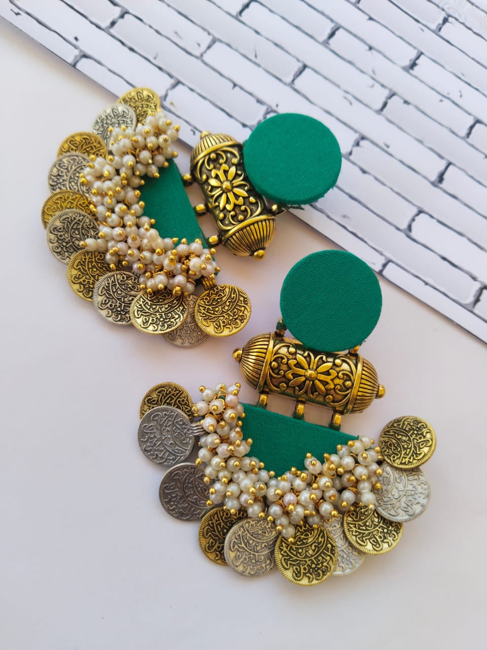 Sea green jhumka earrings with golden tabiz, white beads and golden silver coins on white grey backdrop