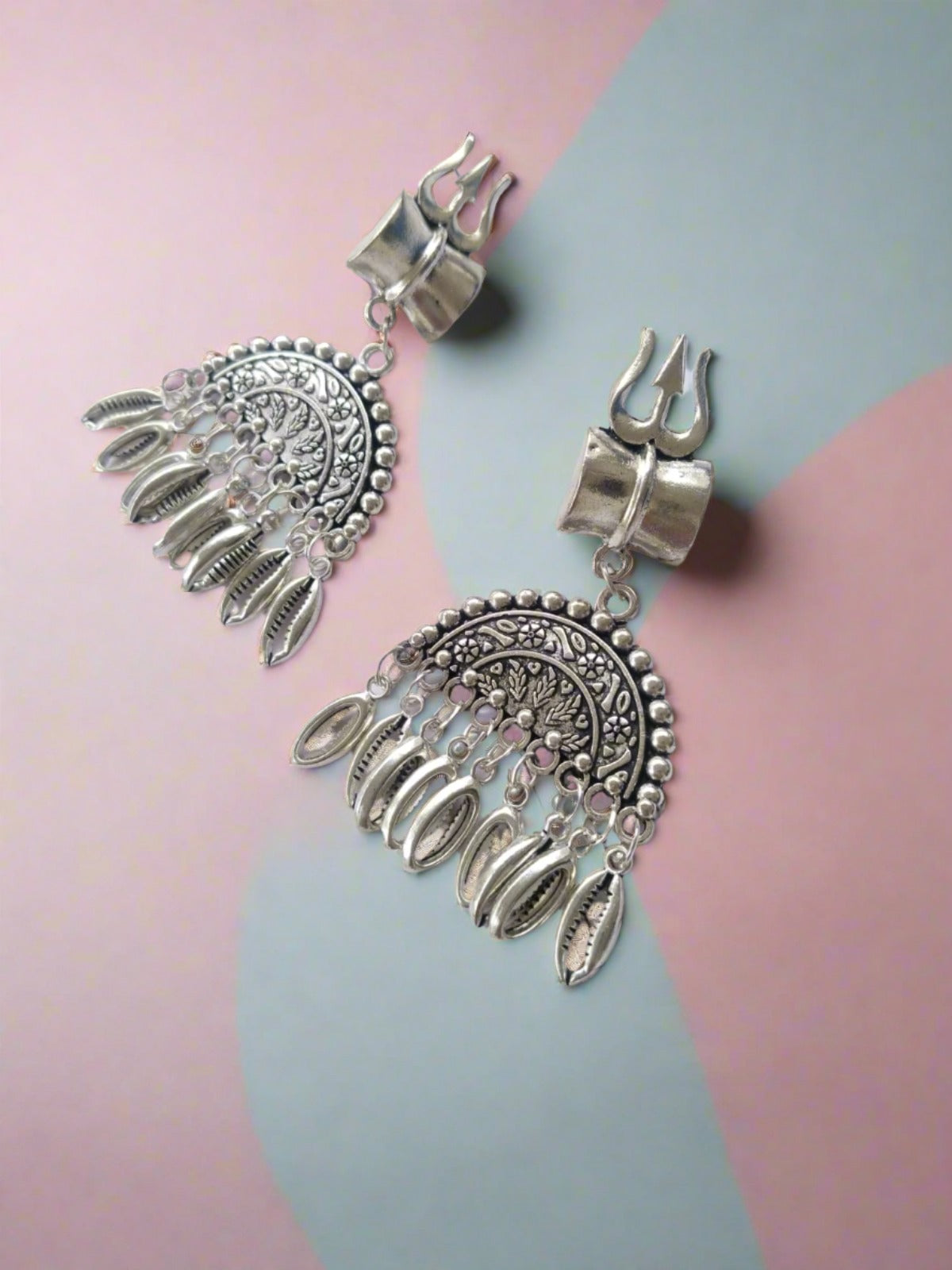 Silver oxidized semi round jhumka earrings with silver beads and trishul charm on white backdrop