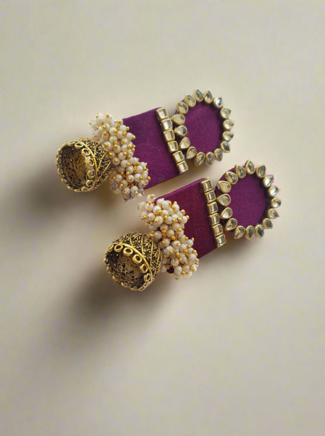Wine purple rectangular jhumka with white and golden beads on white grey backdrop