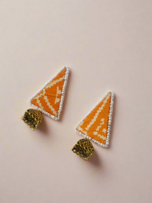 Yellow patola print triangular studs earrings with golden charm on white grey backdrop