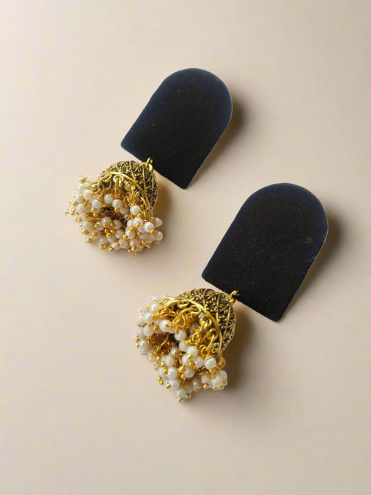 semi oval shape plain black earrings with golden beads at bottom on white backdrop